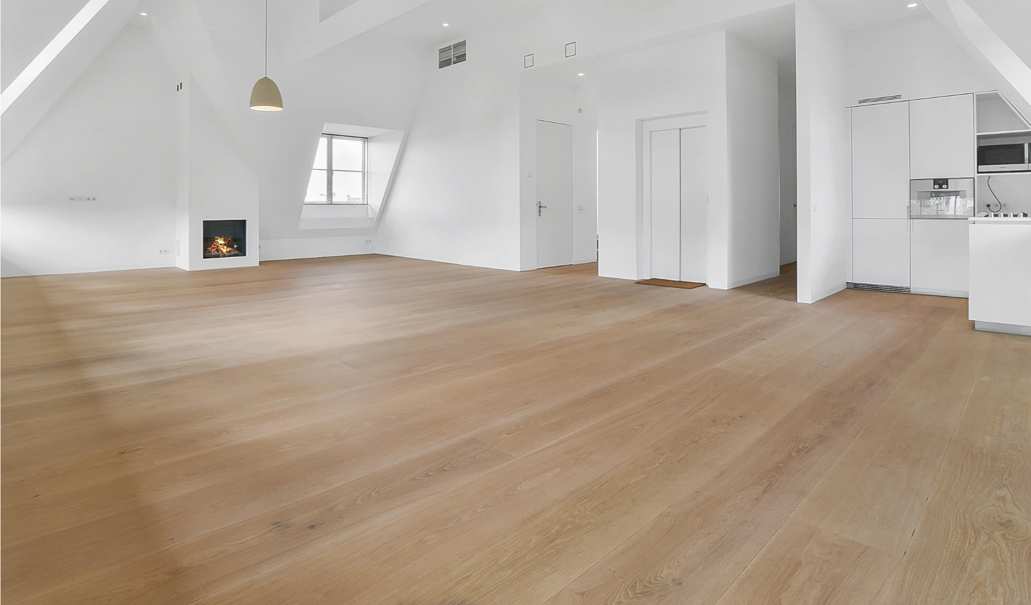 Ocieplenie poddasza użytkowego – wykończone wnętrze z jasną drewnianą podłogą, białymi ścianami i oknem