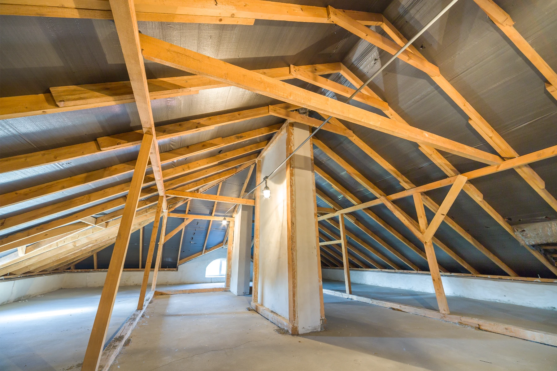Przestronny nieocieplony strych z drewnianą więźbą dachową przygotowany do izolacji poddasza